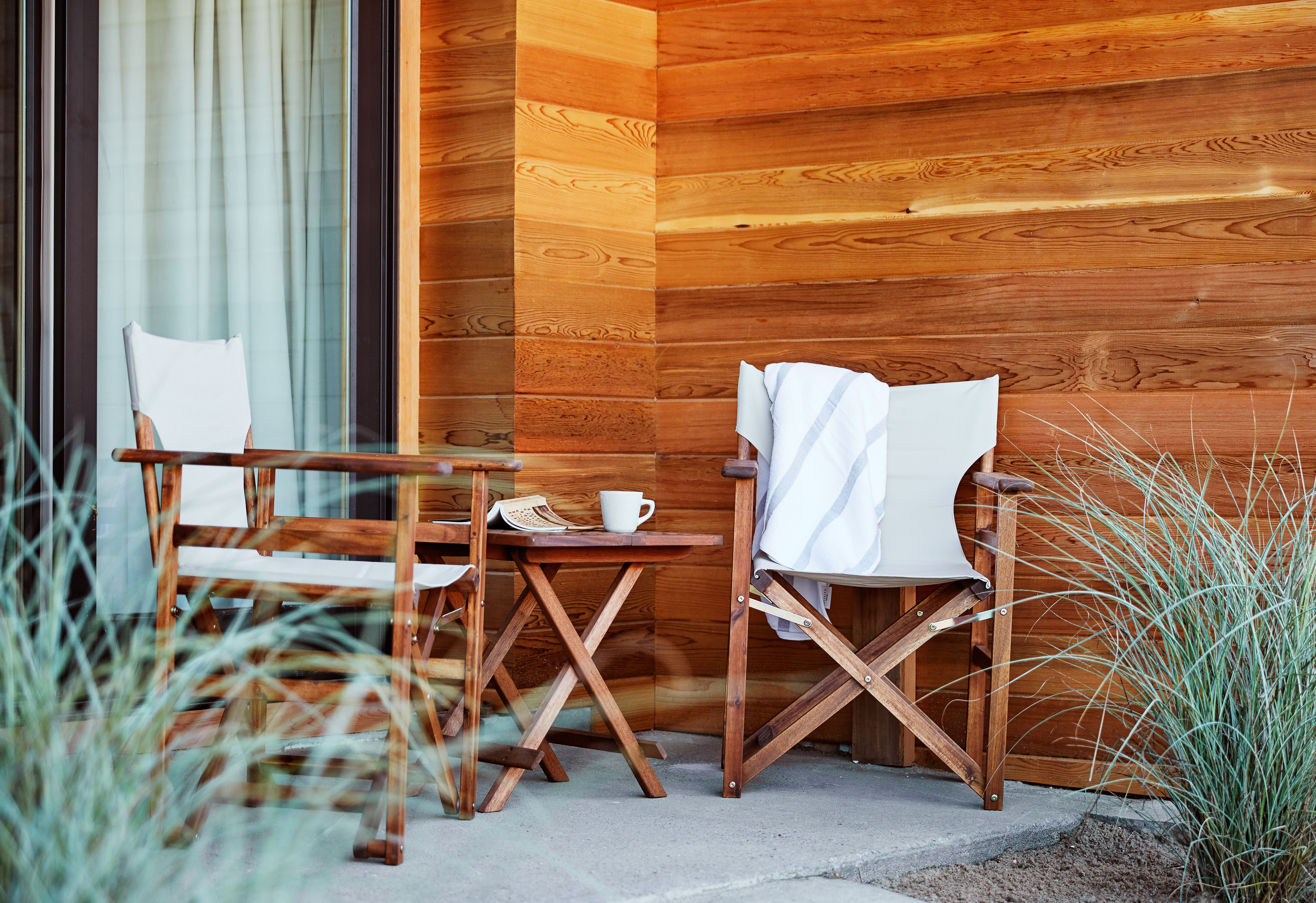 A patio with chairs and a table next to dune grass