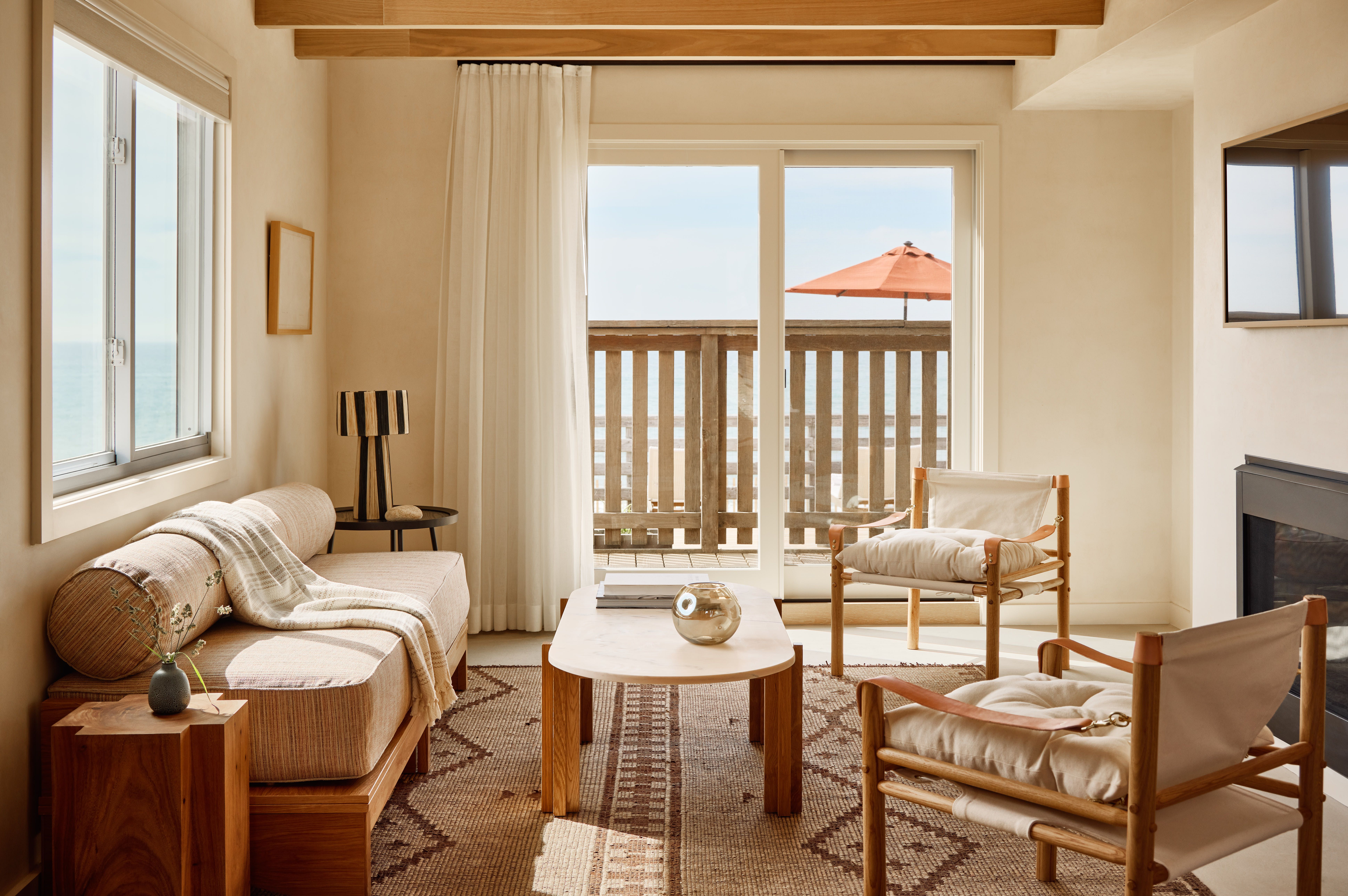 A patio with chairs and a table next to dune grass