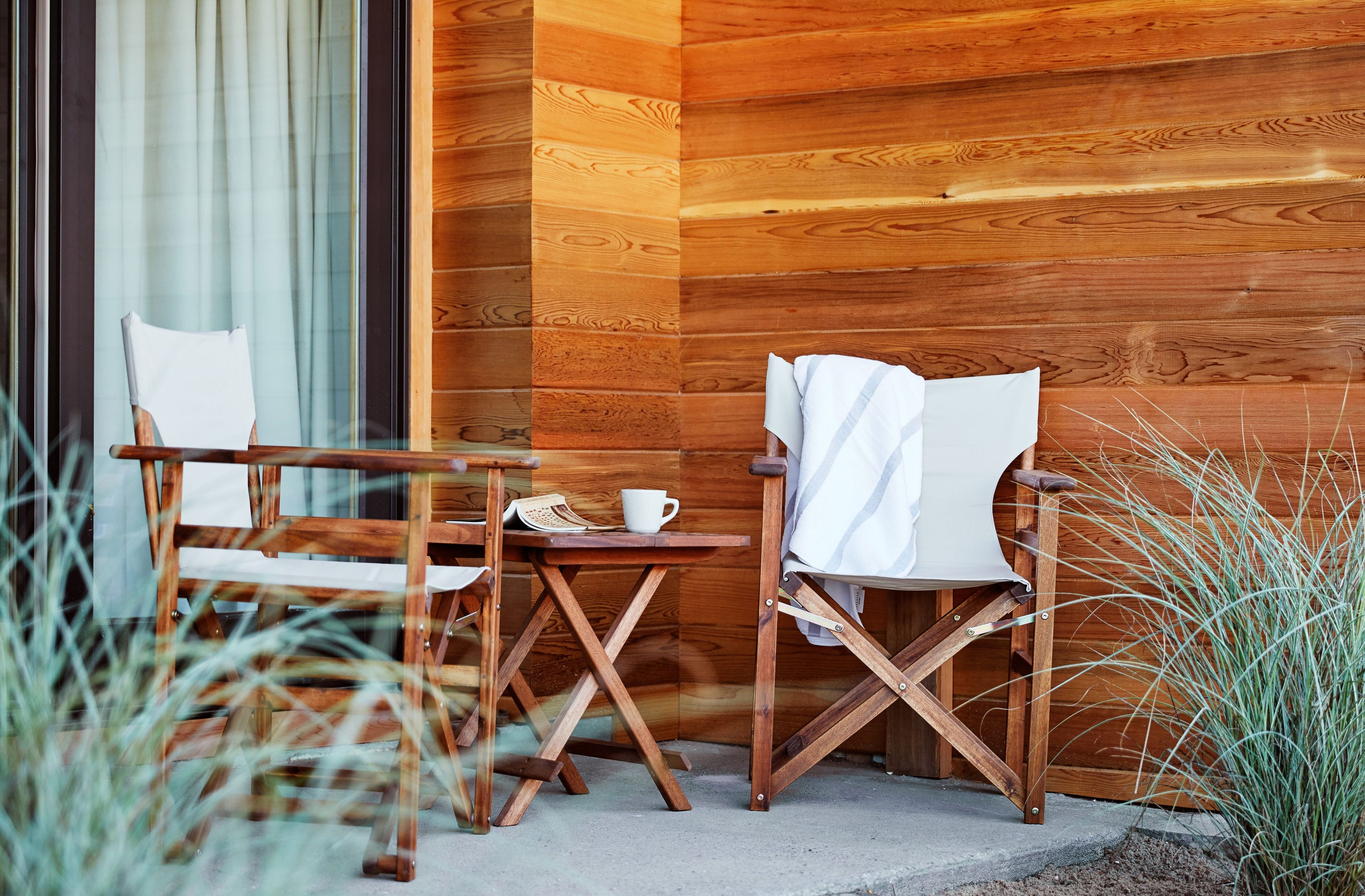 Fabric patio chairs and a side table outside in the shade