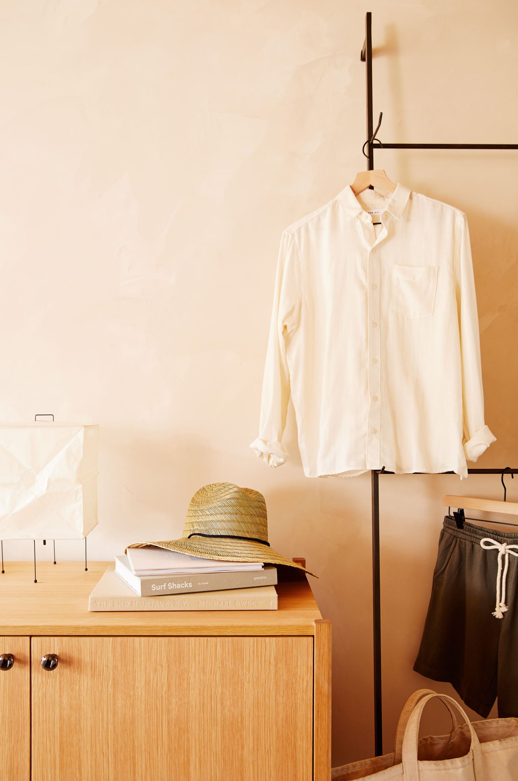 A dresser with items and a sparsely adorned iron clothing rack