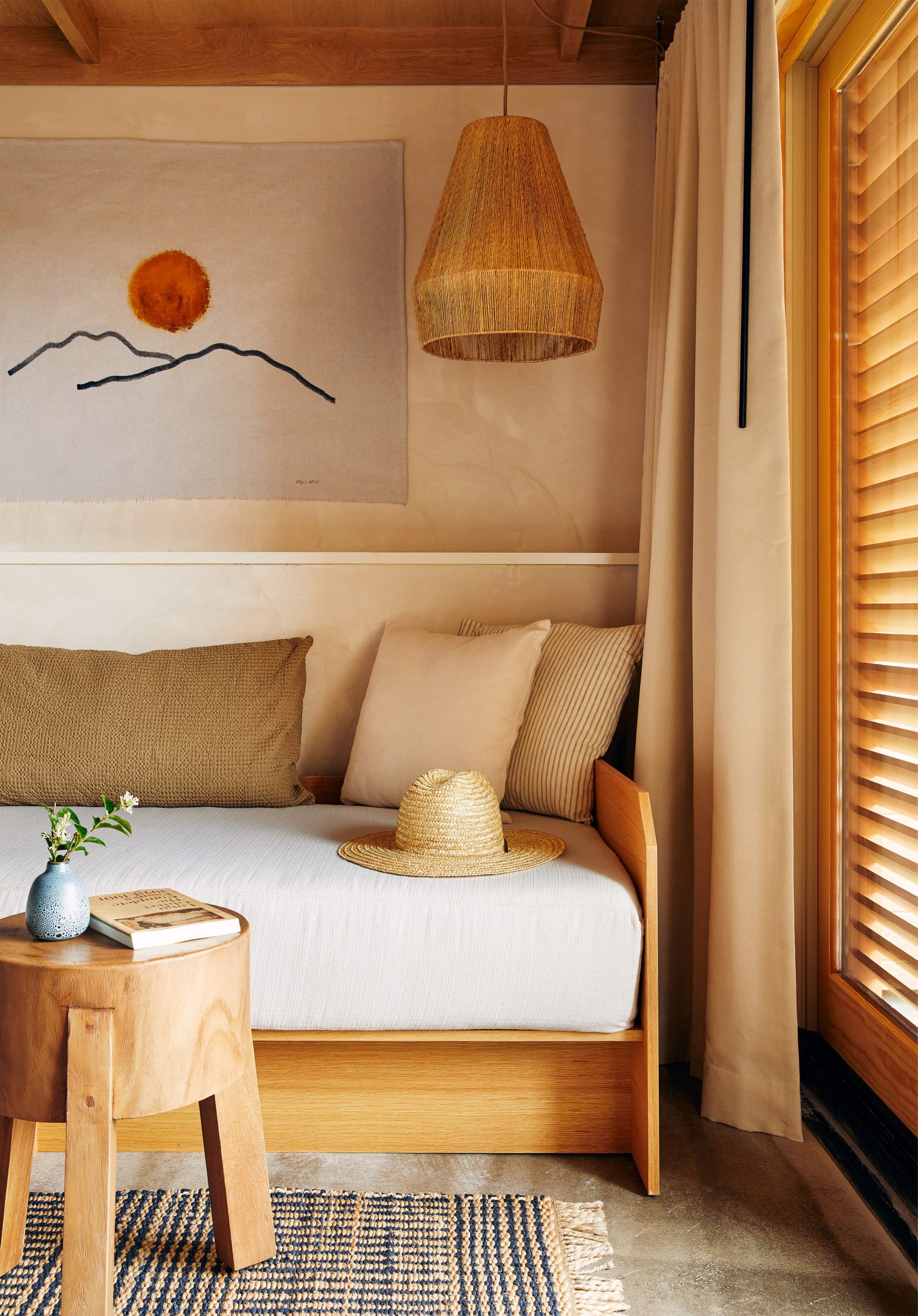 A daybed with pillows and a hat aside a coffee table