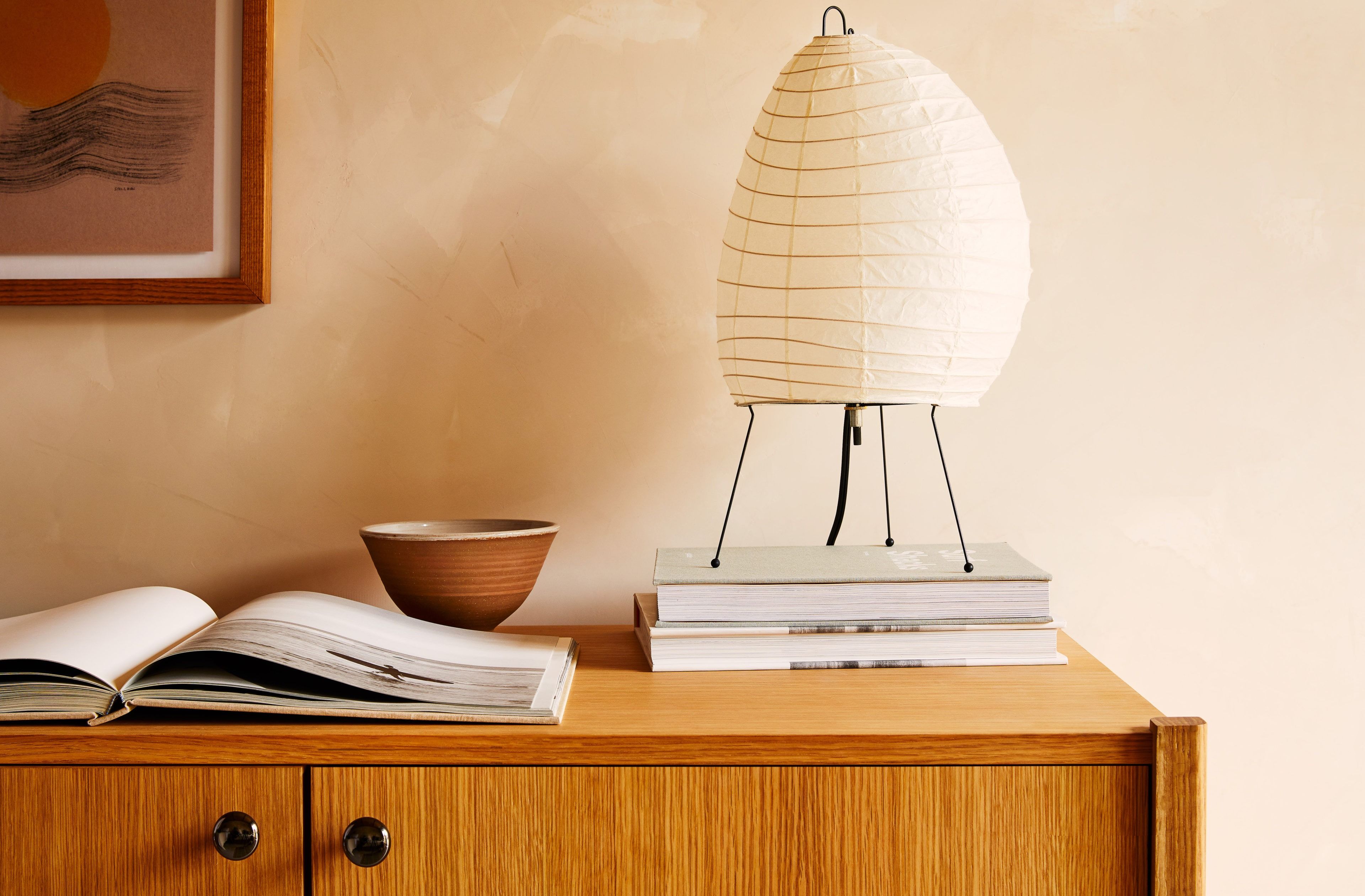 A dresser with a lamp and some large picture books