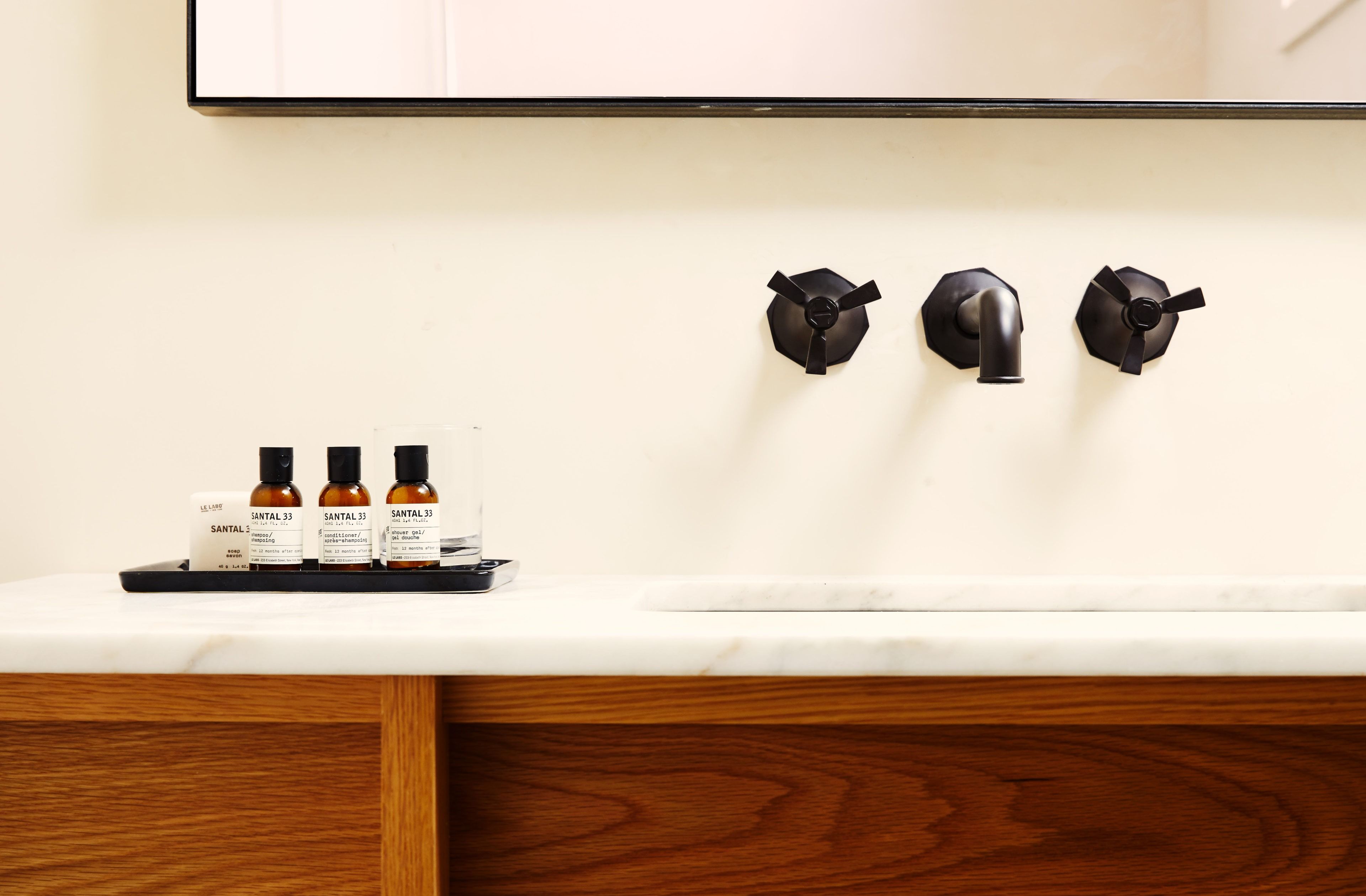A marble bathroom sink with a black wall attached faucet